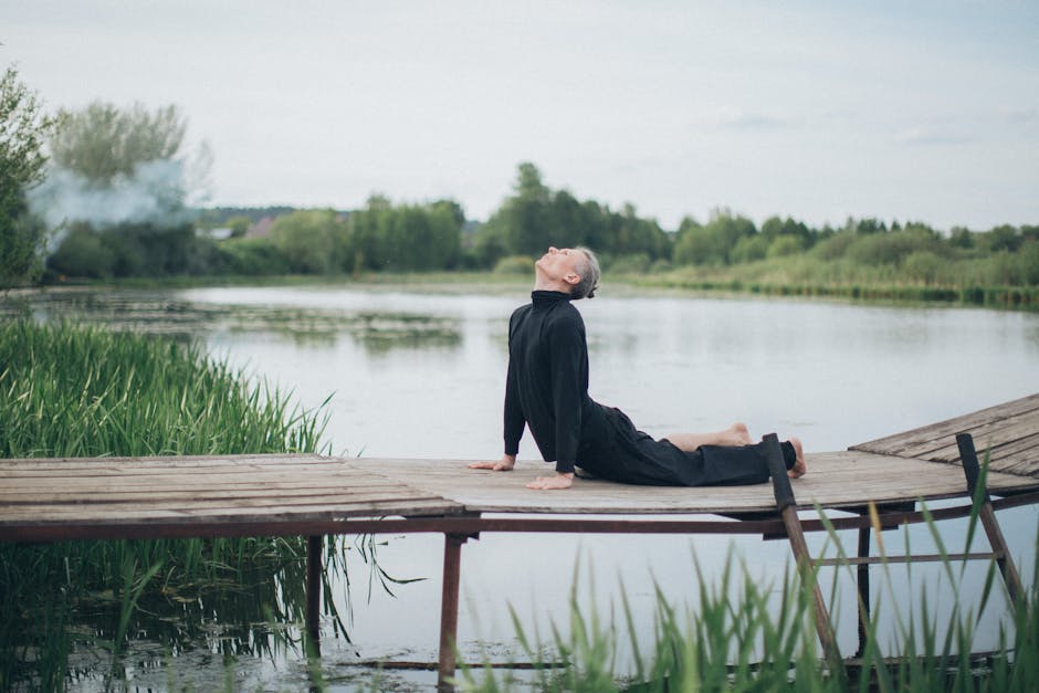 Woman in a peaceful yoga lotus pose on a wooden pier by the lake